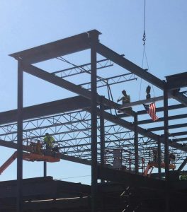 Steel workers secure the final beam into-place-