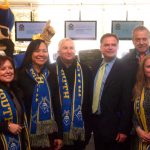 Executive Director of the UMASS Building Authority Katherine Craven (far right), celebrates the opening of the Tripp Athletic Center at UMASS Dartmouth on December 11, alongside UMASS officials including: Maria Furman (far left), Vice Chair of the UMASS Board of Trustees; Dr. Divina Grossman (second from left), Chancellor of UMASS Dartmouth, Massachusetts State Representative Paul Schmid III (second from right), and Arnie the Corsair (back).