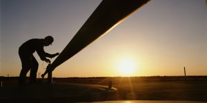 Worker at natural gas booster station, sunset, silhouette